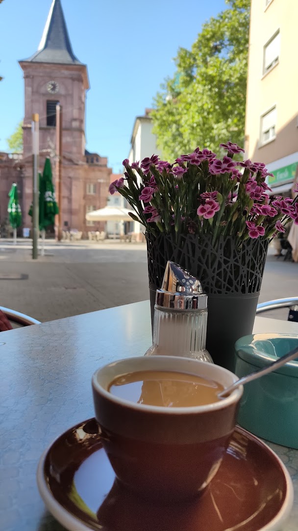 Kaffee auf einem Tisch vor dem Cafe Napoleon mit Karlsruher Stadtkulisse